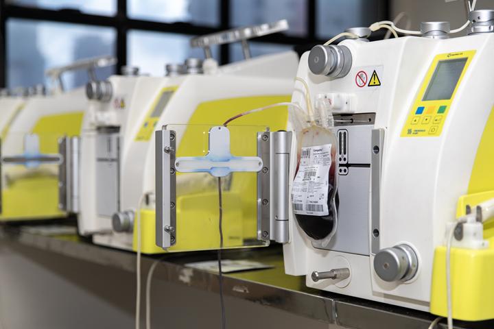 Equipamento automatizado utilizado para processar bolsas de sangue, com tela digital e tubos conectados.