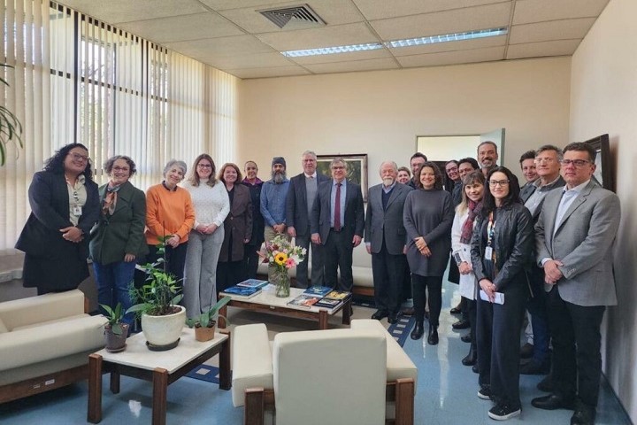 Participantes do evento em pé, lado a lado, posando para uma foto