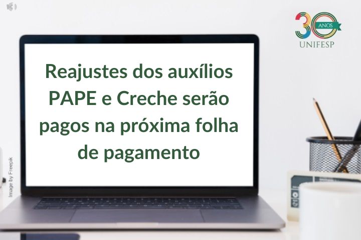 Claro! A imagem mostra um notebook em uma mesa. Na tela do notebook, aparece o seguinte texto em português:  "Reajustes dos auxílios PAPE e Creche serão pagos na próxima folha de pagamento".  No canto superior direito da imagem, há o logotipo da UNIFESP (Universidade Federal de São Paulo), acompanhado da marca de "30 anos". O fundo da imagem é claro, transmitindo um visual limpo e organizado. Há também alguns itens de escritório ao lado do notebook, como um porta-lápis com canetas e lápis.