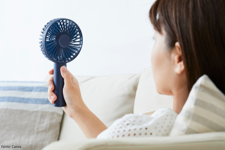 Imagem mostra mulher segurando um mini ventilador portátil 