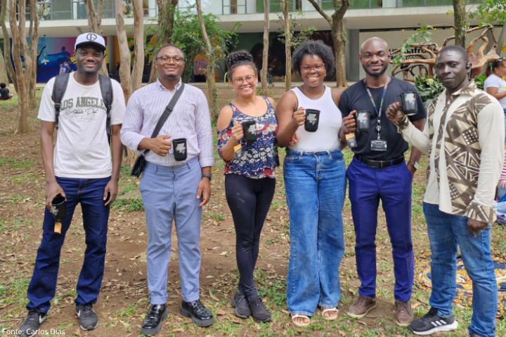 Imagem mostra estudantes internacionais posando para a foto com uma caneca na mão